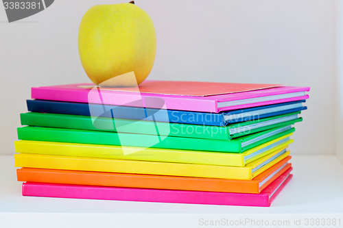 Image of Apple sitting on top of a stack of school books