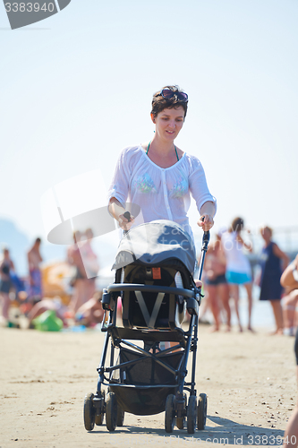 Image of mother walking on beach and push baby carriage