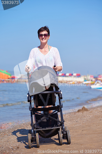 Image of mother walking on beach and push baby carriage