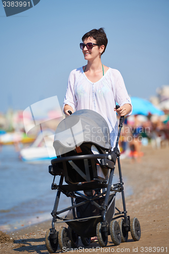 Image of mother walking on beach and push baby carriage