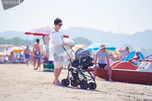 Image of mother walking on beach and push baby carriage