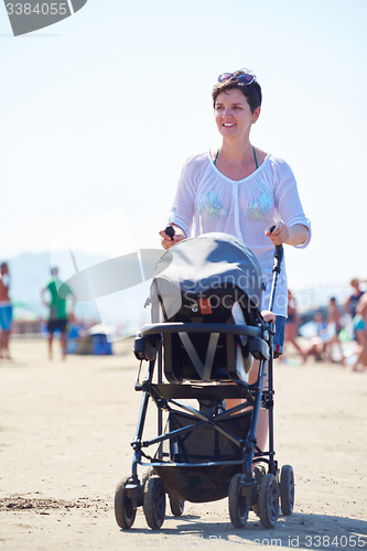 Image of mother walking on beach and push baby carriage