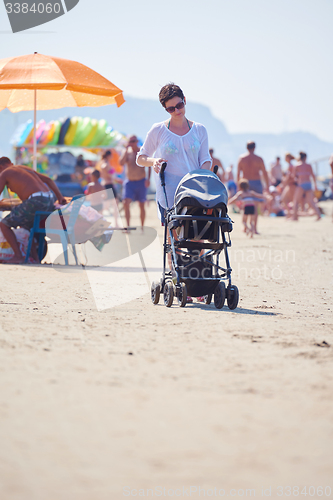 Image of mother walking on beach and push baby carriage