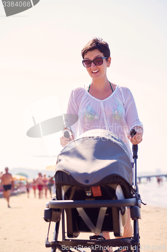 Image of mother walking on beach and push baby carriage