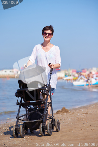 Image of mother walking on beach and push baby carriage