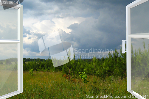 Image of opened window to summer field before thunder 
