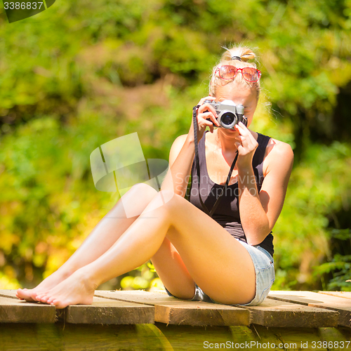 Image of Woman in nature with retro camera.