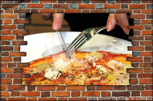 Image of broken brick wall and fork knife and tasty pizza