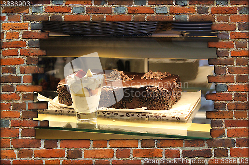 Image of hole in wall and counter with ice-cream and cakes