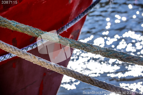 Image of Mooring line of a trawler in backlight with water reflections