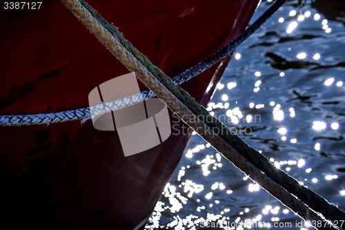 Image of Mooring line of a trawler in backlight with water reflections