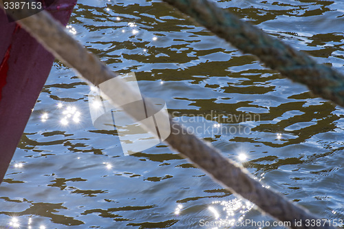 Image of Mooring line of a trawler in backlight with water reflections