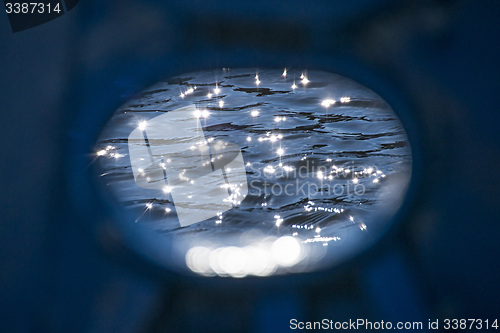 Image of Ship scupper in back lighting with water reflexions