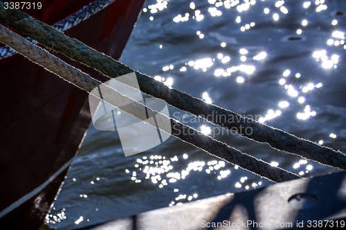 Image of Mooring line of a trawler in backlight with water reflections