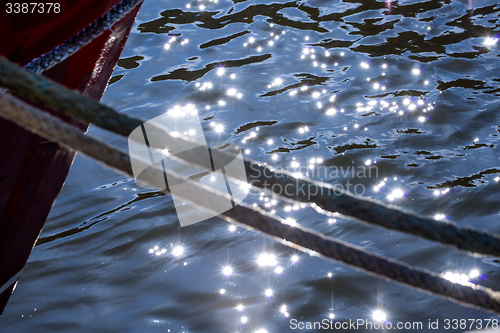 Image of Mooring line of a trawler in backlight with water reflections