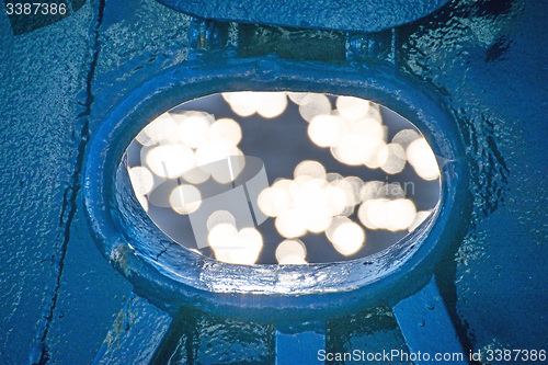 Image of Ship scupper in back lighting with water reflexions