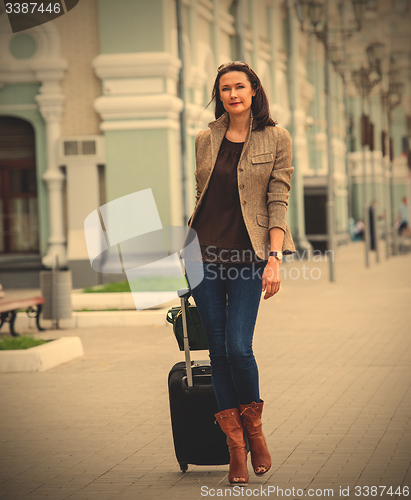 Image of beautiful business woman with a suitcase walking on the apron la