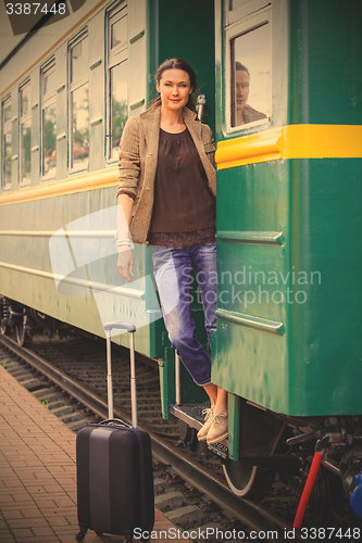 Image of beautiful adult woman on the steps of the passenger car