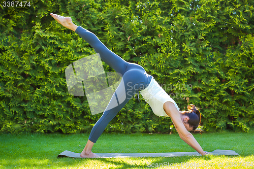 Image of adult woman doing yoga in sunny morning park