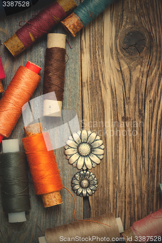 Image of vintage buttons and old reels of varicolored thread on the text