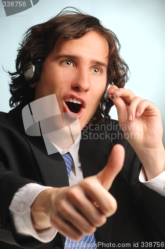 Image of young handsome long hair operator with headset doing sucsess ges