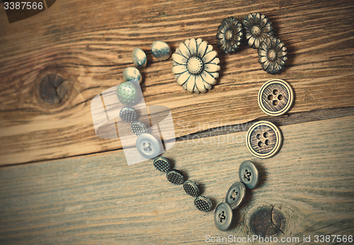 Image of vintage buttons heart on old textured boards