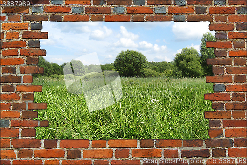 Image of hole in the brick wall and view to summer field