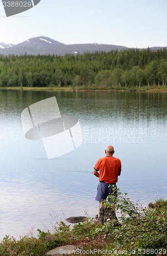 Image of Man fishing by a lake