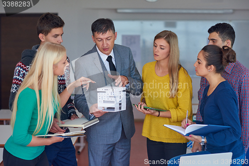 Image of group of students working with teacher on  house model