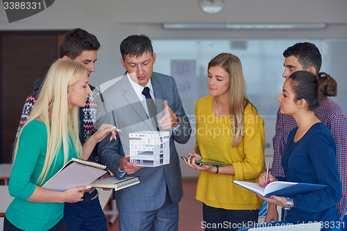 Image of group of students working with teacher on  house model