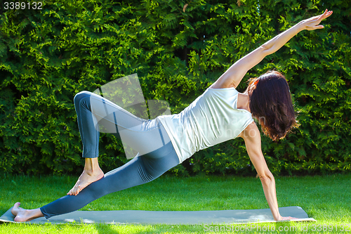 Image of adult woman doing yoga on green grass