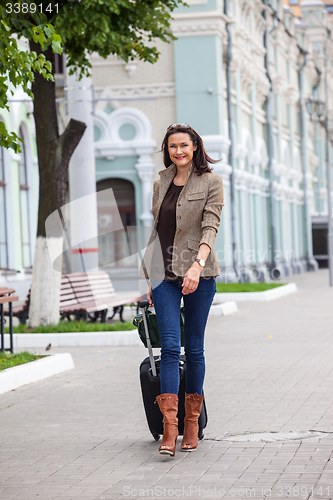 Image of pretty adult woman with a suitcase walking on the apron landside