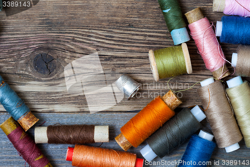 Image of thimble and spools of thread on an aged wooden surface