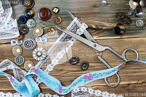 Image of buttons, lace, tape and a dressmaker scissors