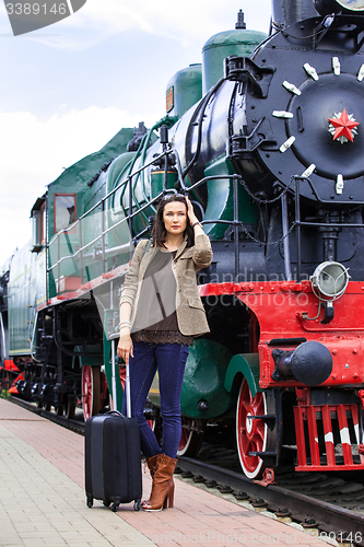 Image of woman traveler with luggage near retro puffer