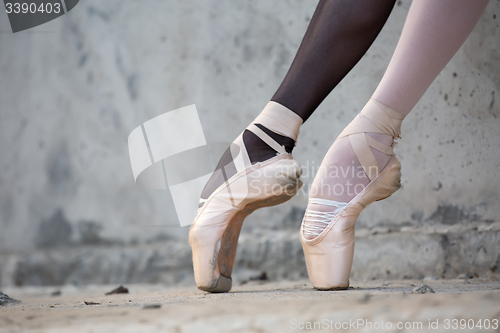 Image of Ballerina feet close-up on a background of textured concrete wal