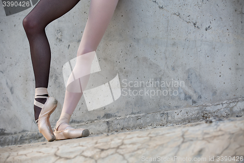 Image of Ballerina feet close-up on a background of textured concrete wal