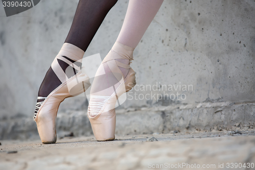 Image of Ballerina feet close-up on a background of textured concrete wal