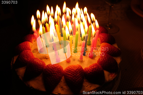 Image of birthday strawberry cake with lighted candles