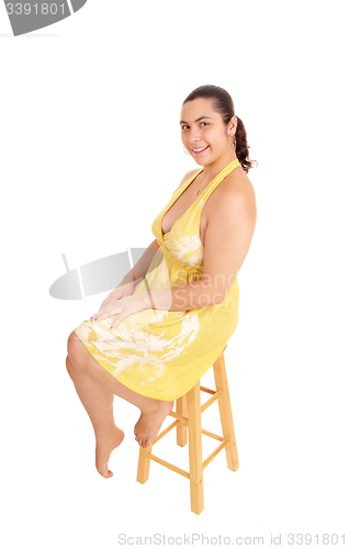 Image of Woman in yellow dress sitting on chair.