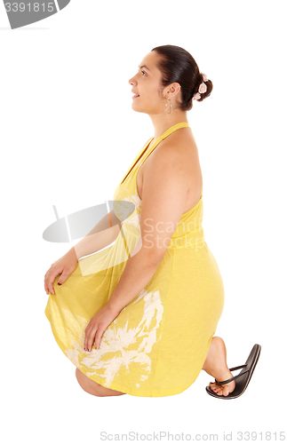 Image of Pretty woman in yellow dress kneeling.
