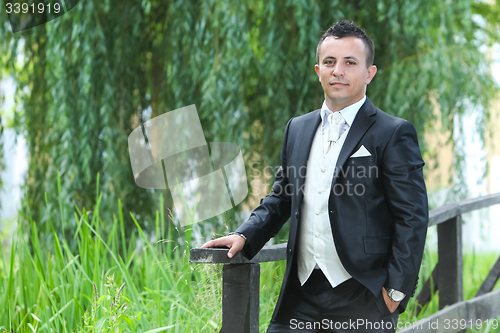 Image of Groom posing on wooden bridge