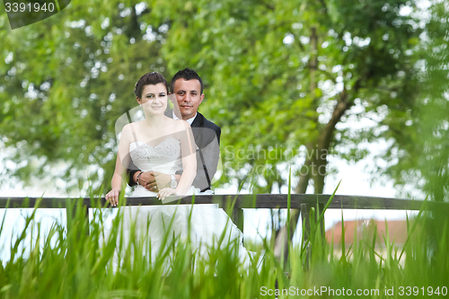 Image of Married couple posing on wooden bridge