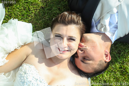 Image of Newlyweds kissing on grass