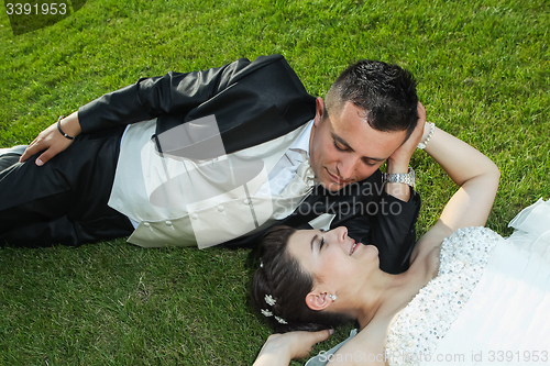 Image of Bride and groom resting on grass