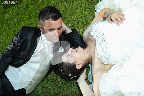 Image of Bride and groom resting on lawn