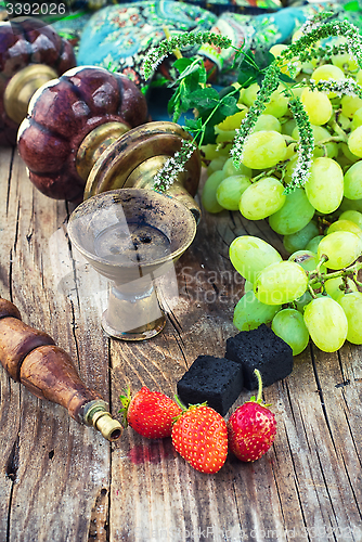 Image of Hookah amid bunches of grapes and strawberries