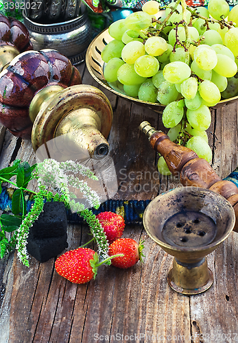 Image of Hookah amid bunches of grapes and strawberries