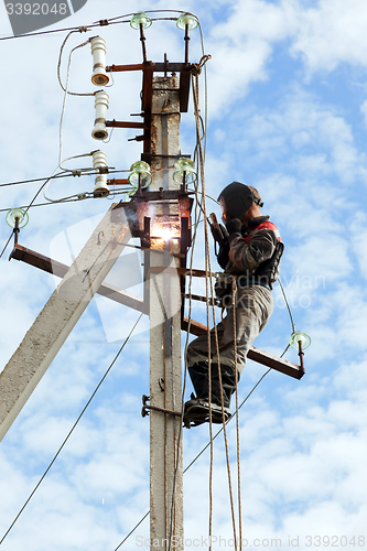 Image of Electrician connects metal parts ground loop on a pole transmiss