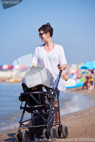 Image of mother walking on beach and push baby carriage